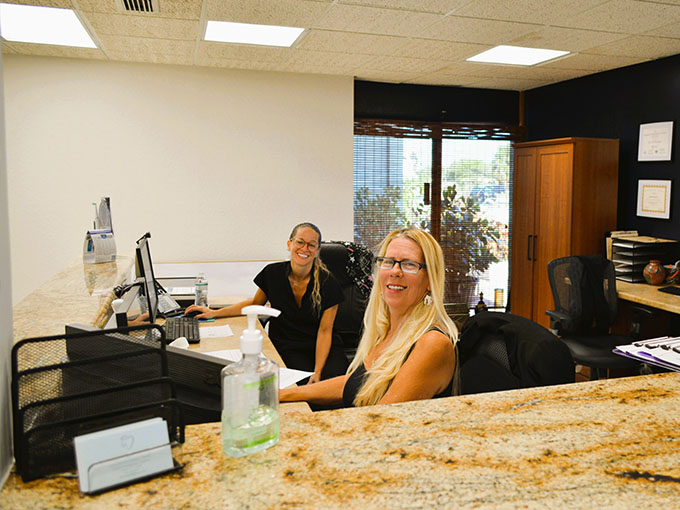 Two individuals sitting at a desk in an office setting.