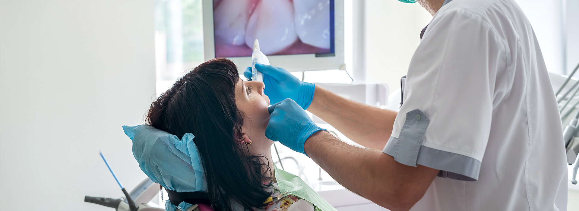 A dental professional performing a procedure on a seated patient s mouth.