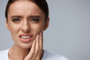 young woman holding her jaw in pain.